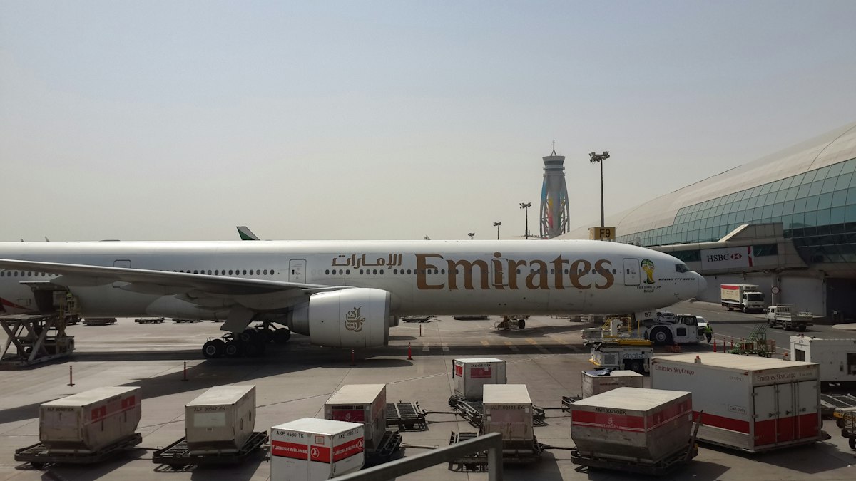 Самолёт Emirates у терминала аэропорта Дубая, на заднем плане диспетчерская вышка