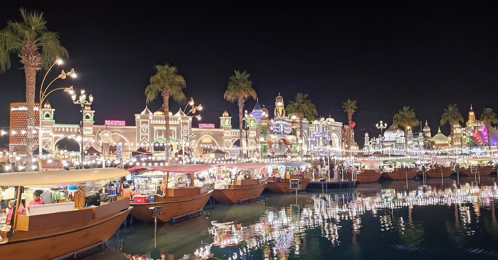 Global Village вечером: павильоны и лодки на воде в огнях