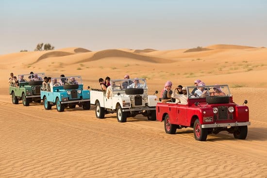 Колонна ретро Land Rover едет по пустыне на традиционном сафари