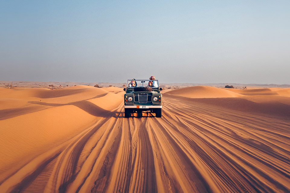 Винтажный Land Rover едет по песчаным дюнам в заповеднике Дубая