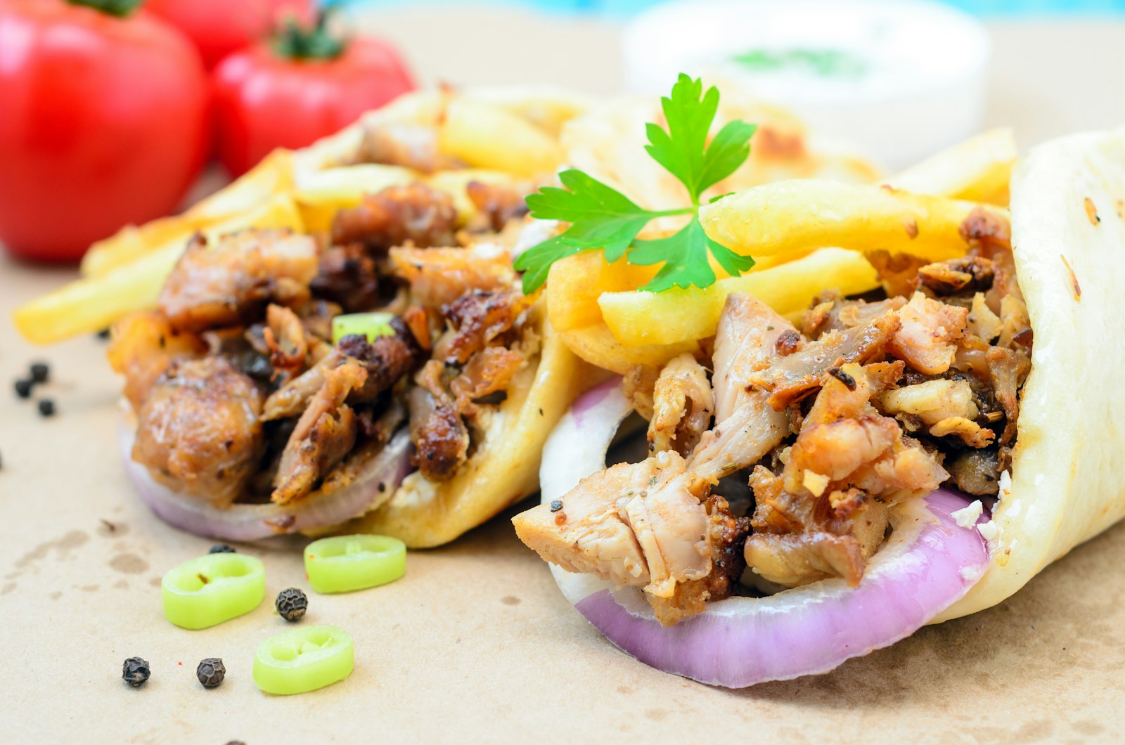 Две шаурмы в лепёшке с курицей, картофелем фри и красным луком на крафтовой бумаге
